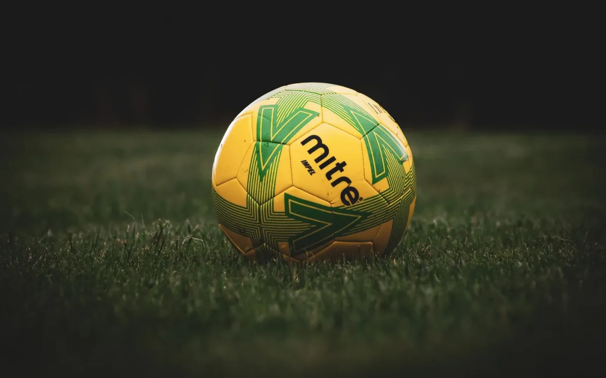 Minge de fotbal galbenă cu model verde, pe gazon