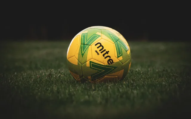 Minge de fotbal galbenă cu model verde, pe gazon