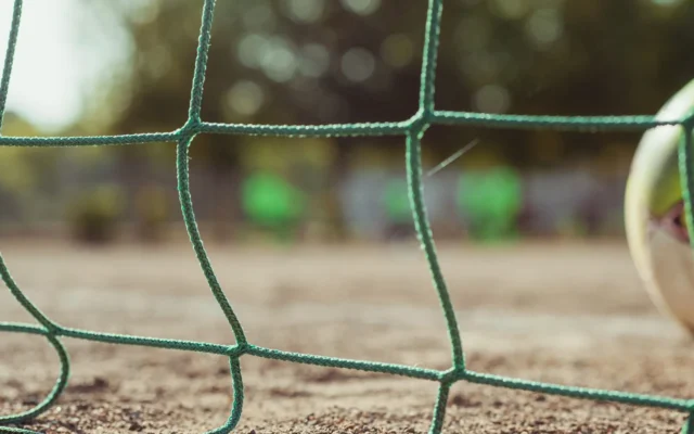 Plasă verde de poartă și o minge de fotbal la marginea cadrului
