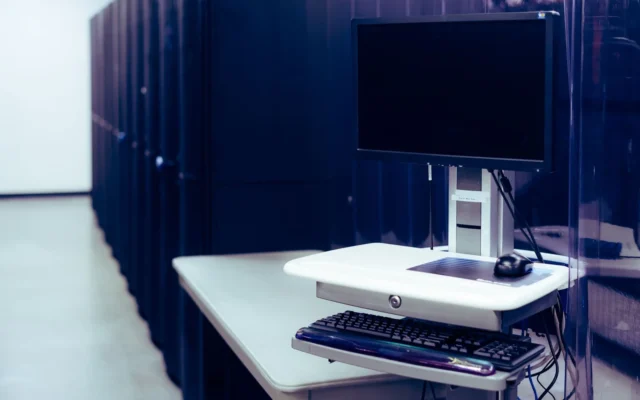 Monitor și tastatură lângă rackuri într-o sală de servere
