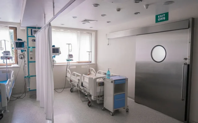 Paturi goale și echipamente medicale într-un salon de spital, cu perdea de separare