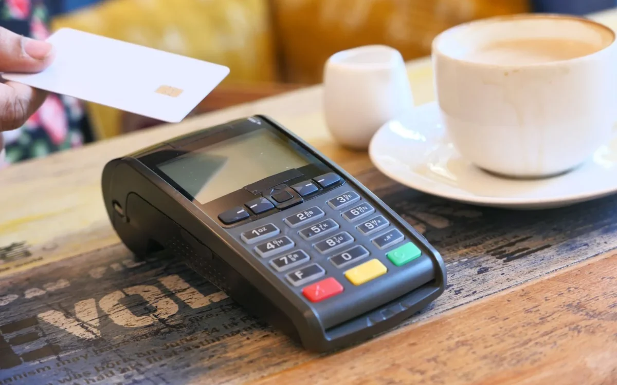 Card și terminal electronic de plată lângă o ceașcă.